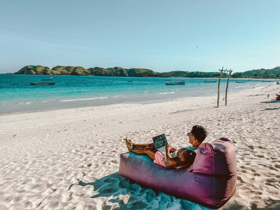 Un apprenant travaille sur son ordinateur portable au bord de la mer